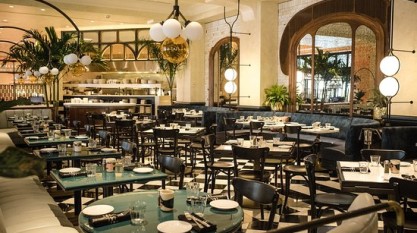 Inside of Louie Louie, a restaurant with green tables and art deco-inspired fixtures.