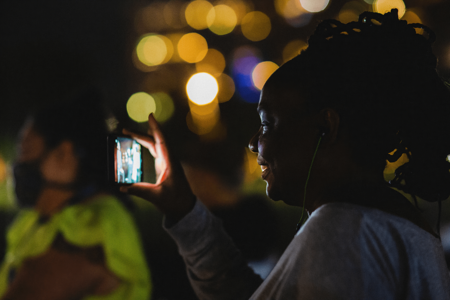 A photo of a person holding taking a picture with their phone. They are smiling.