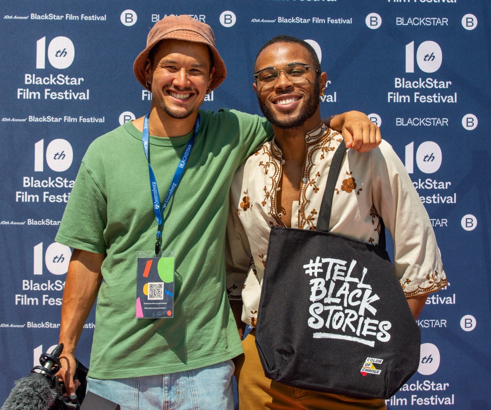 A photo of Aidan Un and another person standing in front of the 2021 BlackStar Film Festival step-and-repeat. They are smiling