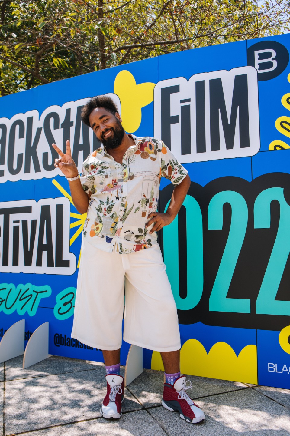 A person stands in front of the BlackStar Film Festival photo wall.