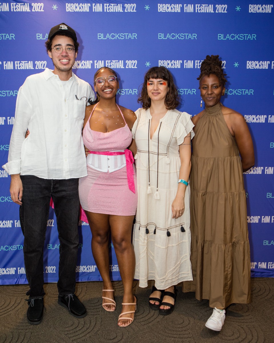 The four lab filmmakers pose in front of the step-and-repeat, they are smiling.