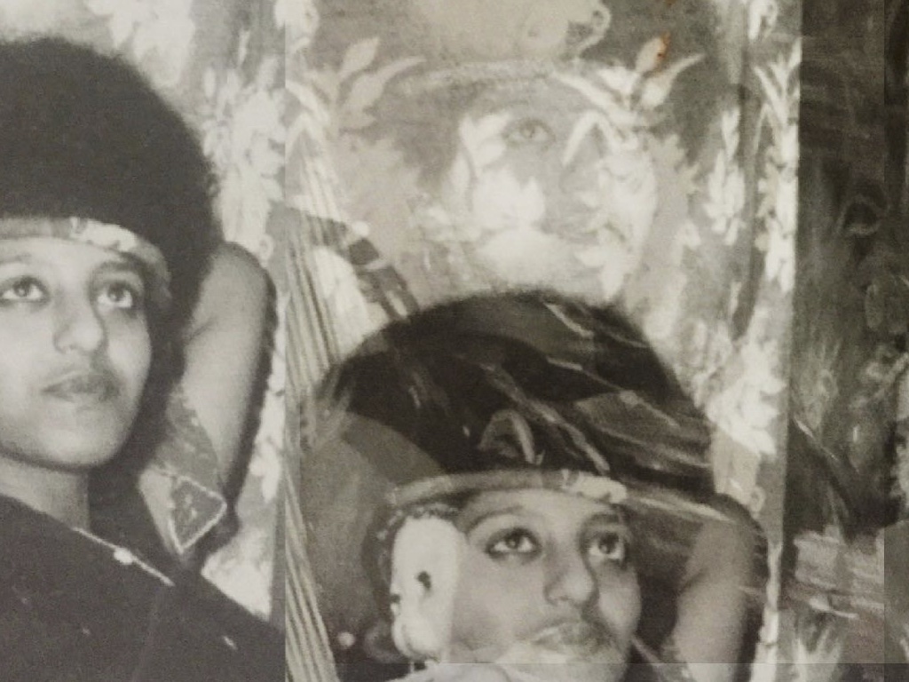 A black-and-white photo, it shows two Ethiopian people looking into the distance. There is a decorative cloth behind them.