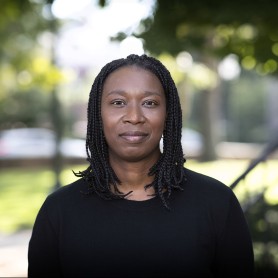 A photo shows a portrait of Claudrena N. Harold outdoors looking directly at the camera.