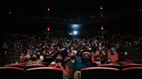A photo from the 2022 BlackStar Film Festival. It shows a movie theater packed with people. They are wearing face masks.