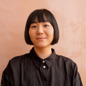 A headshot of Catherine Lee. She is an Asian woman, she has a short black bob. She is smiling softly at the camera.