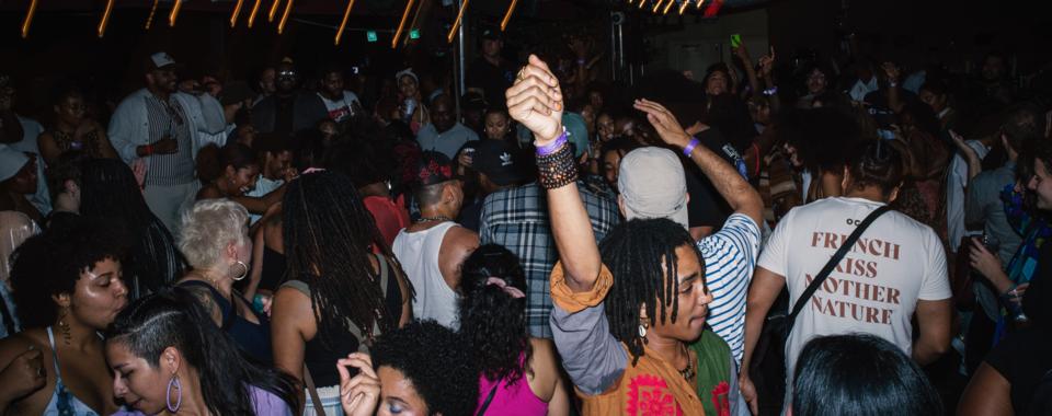 A crowd shot of people dancing at a party. The lights glow around them.