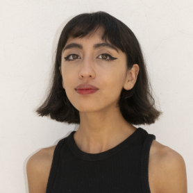A picture of a woman named Mir Morales Rosales. She is posed elegantly towards the camera with a short brown bob, thick black eyeliner, and a simple black tank top against a blank white background.