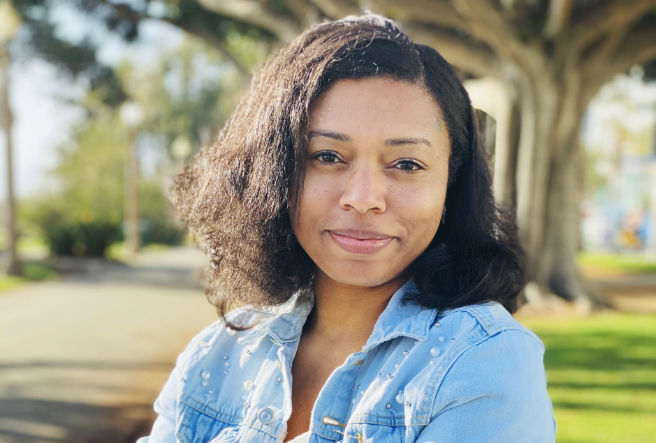 A headshot of Nijla Mu'min. She is a Black woman. She is smiling softly at the camera.