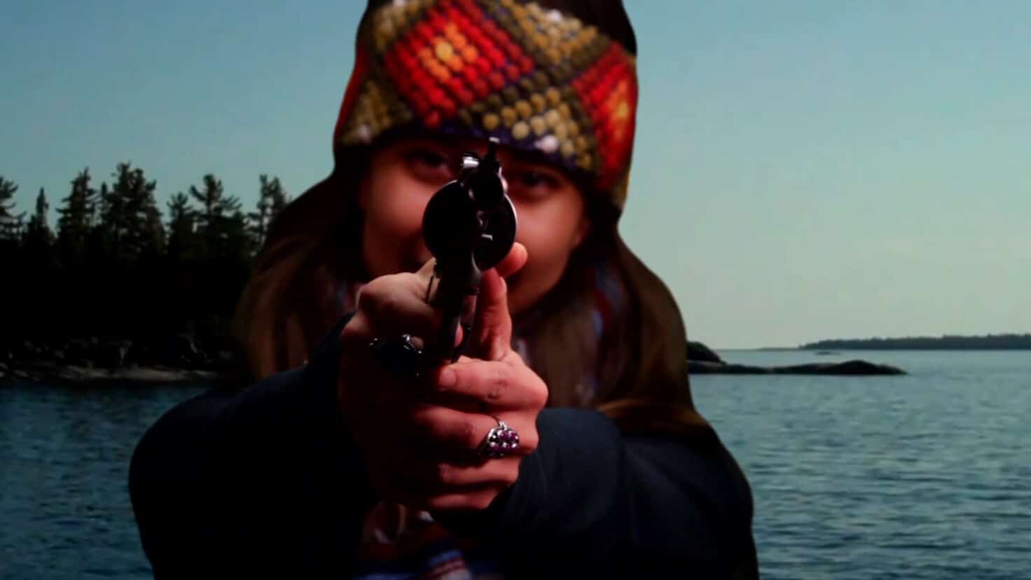 A person points a gun into the camera in a film still.