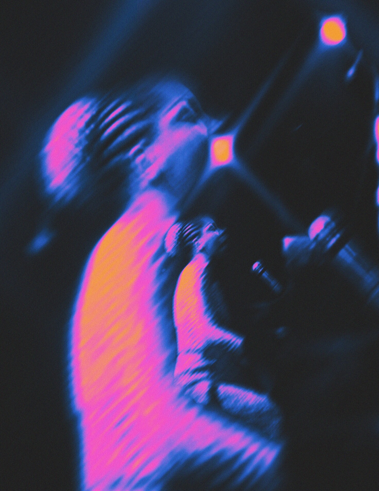 A blurred rendering of Nina Simone sitting at a piano on stage with bright lights above her. The image is a range of blue, pink, orange, and dark yellow.