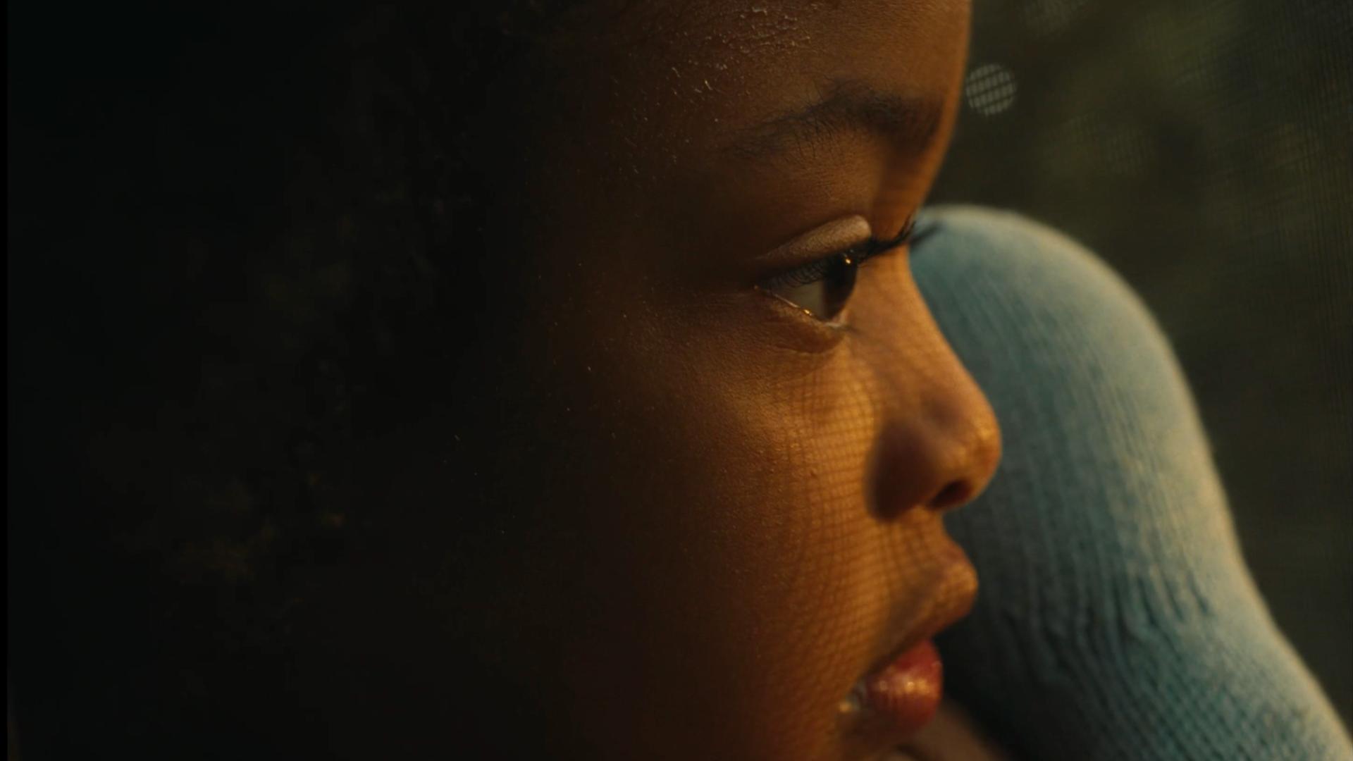A film still from all the love i could handle shows the side profile of a young Black girl curiously staring at something off screen.