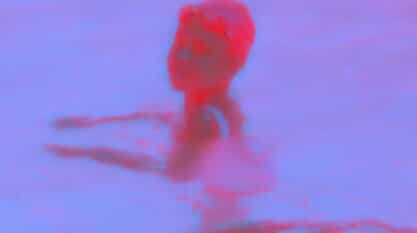 A hot pink and light purple dual-toned film still from nobody’s word shows a figure presumably standing in a body of water looking over their shoulder. The bottom of the still reads: “500 years ago…wow.” in small white text.