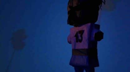 A film still from Piñata Prayers shows the back of a piñata that faces a blue wall with a palm tree pattern. The piñata resembles a person playing a sport. It wears the number thirteen on its back.