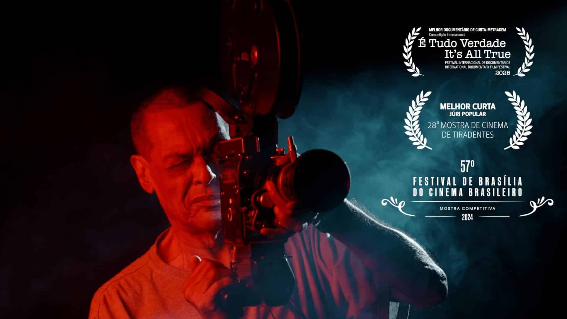 the image show AFranio Vital, a black man of 72 years old holding a camera over a red light and pointing it to the watcher. In the background we see smoke and black.