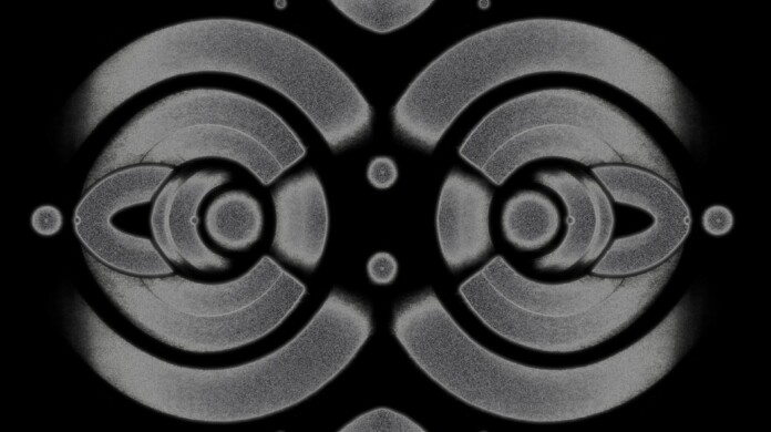 Abstract symmetrical grey patterns of circles create a diamond shape with teardrop-shaped ends on the top and bottom.