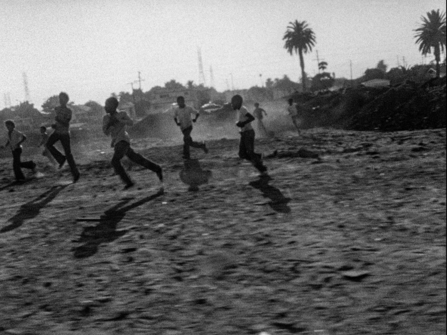 A black and white image from the film Killer of the Sheep (1978). It features a group of Black kids running on a field.