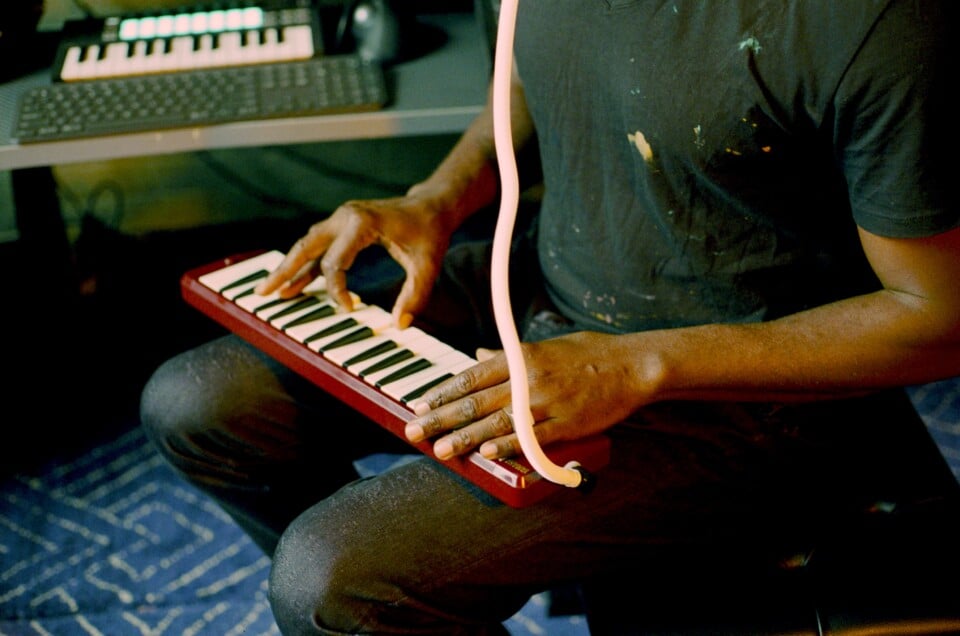 A close-up image of Sanford Biggers’ hands while he plays a melodica.