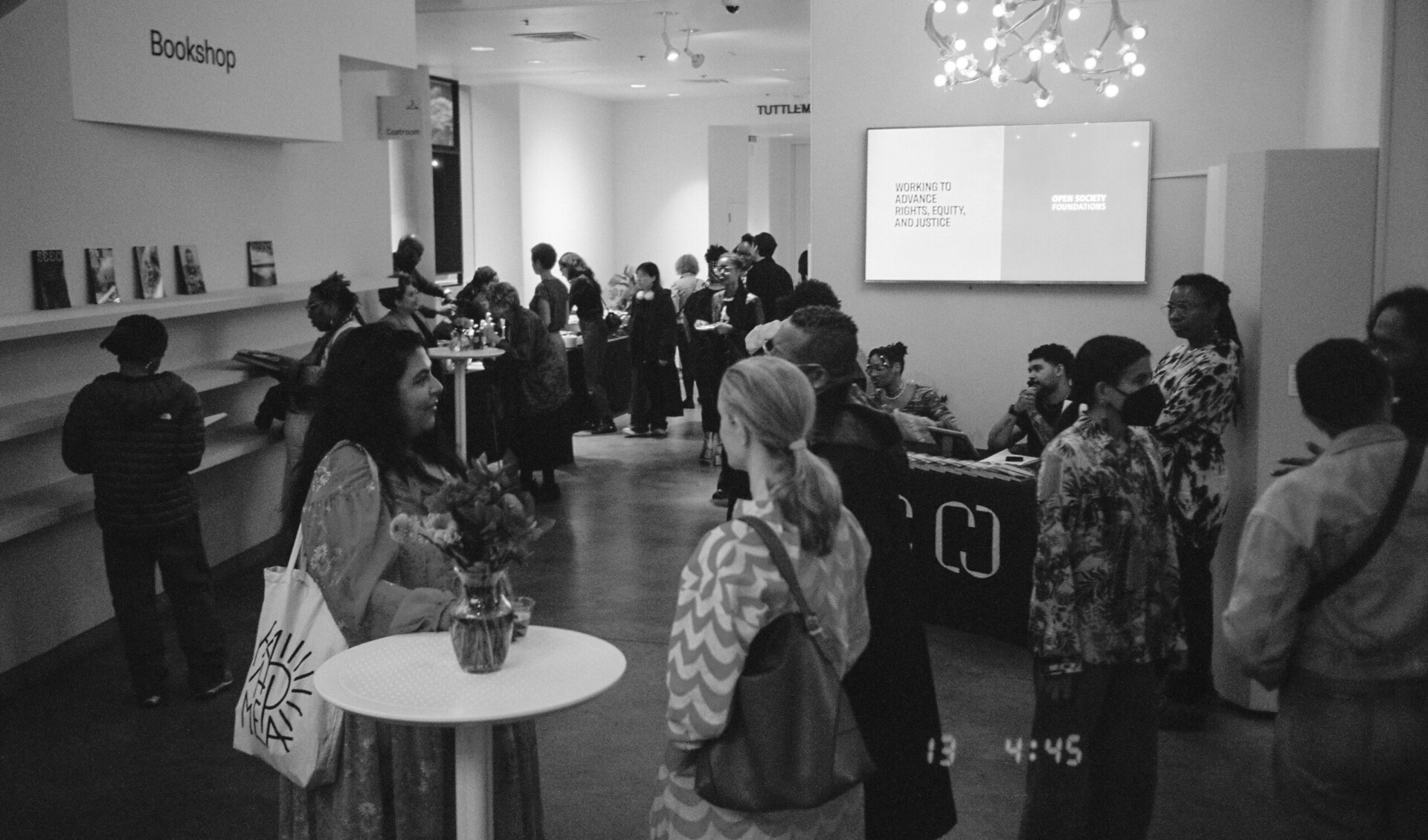 A black-and-white from the Seen 008 launch, it shows a group of people gathered and chatting with one another.