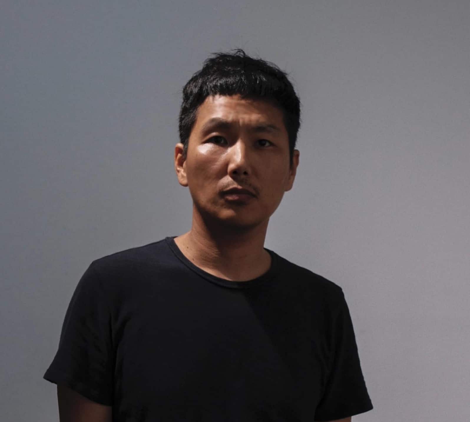 A headshot of Tenzin Phuntsog. He is an Asian man, is a wearing a black shirt and is looking directly at the camera.