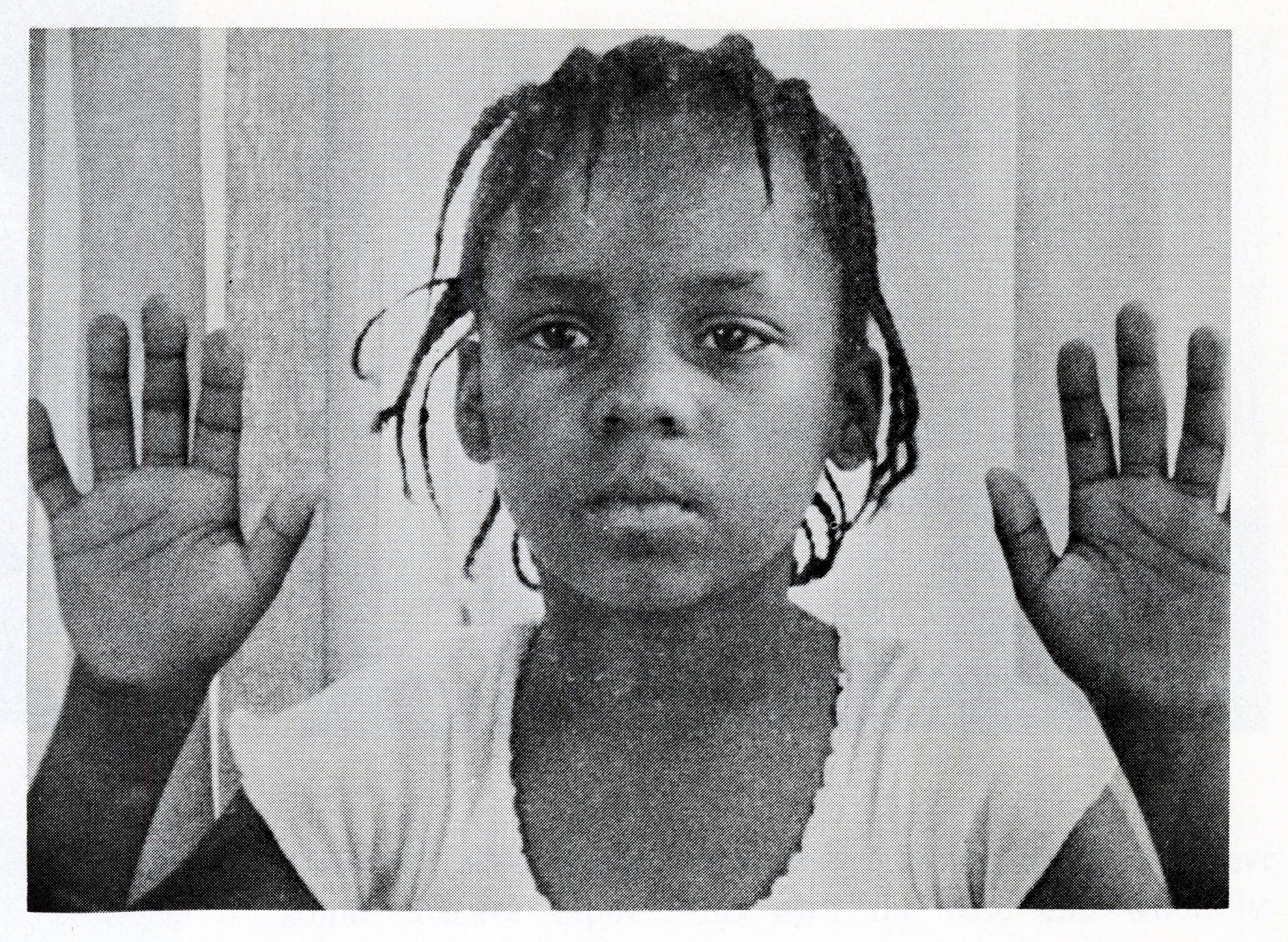 Black and white still from the film "Your Children Come Back to You" shows a young girl with short braids. She raises her hands up and turns her palms towards the camera.