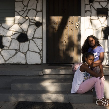 A still from A Love Song for Latasha shows two young girls sitting on the steps of a house in Los Angeles.