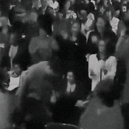 A visual from Revival! The visual looks like a still from an old black-and-white movie. It shows a crowd of people dressed formally, their faces are blurred.