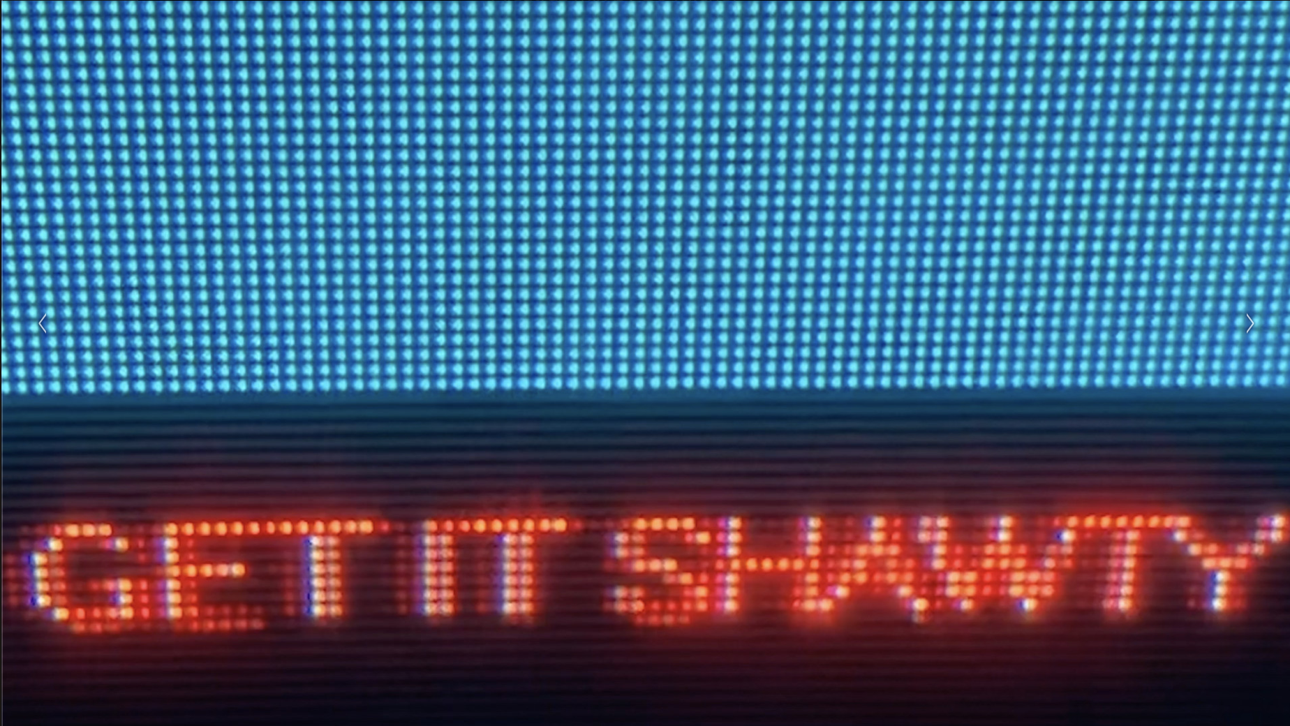 A close up of an electronic sign billboard that says "Get it Shawty" in red lights against a black background, and below blue lights