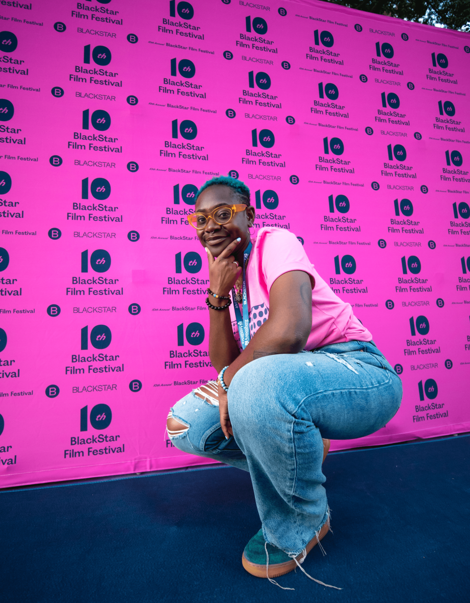 A photo of Animah Danquah posed in front of the 2021 BlackStar Film Festival step-and-repeat. She is swatting and smiling.