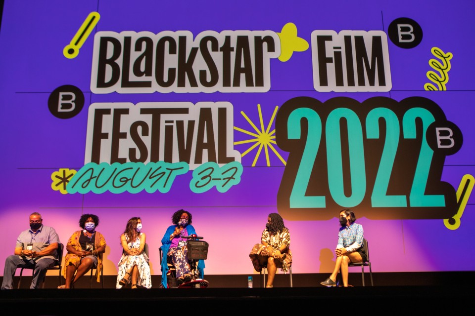 A photo of six people on sitting on stage in front of a screen with the BlackStar Film Festival banner.
