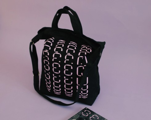 Seen tote bag in black and lilac sits against a lilac backdrop with an issue of Seen barely visible in the frame.