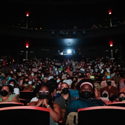 A photo from the 2022 BlackStar Film Festival. It shows a movie theater packed with people. They are wearing face masks.
