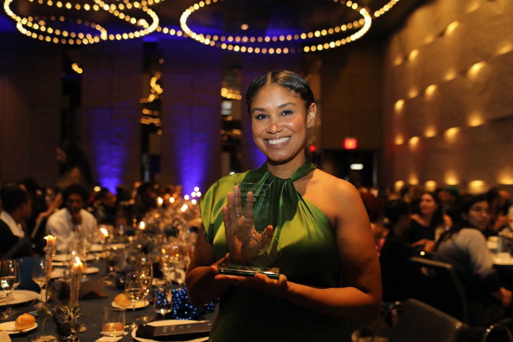 Shannon Maldonado, founder and creative director of YOWIE, poses with her 2023 Luminary Award in a brightly lit ballroom.