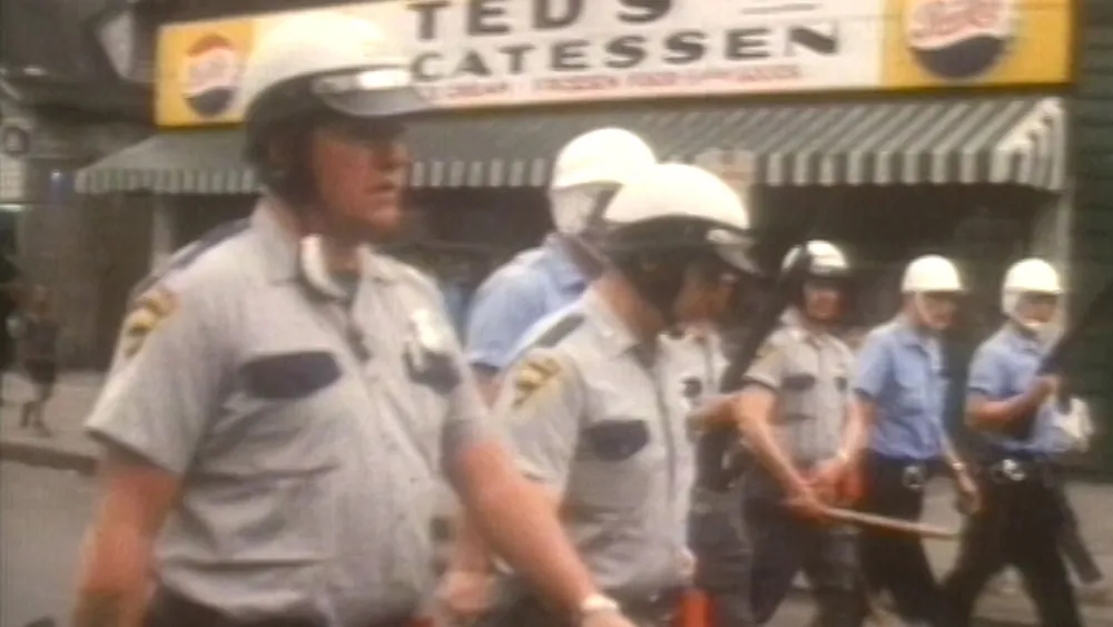 A still from Power. It shows a group of police officers marching down a city block.
